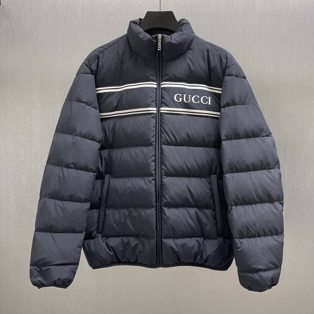 Gu 拉链头尼龙羽绒夹克 Size : S-Xl Gucci标识以别出心裁的色彩和面料组合呈现早秋系列单品。这款轻质羽绒夹克以海军蓝尼龙匠心打造，胸前缀饰guc