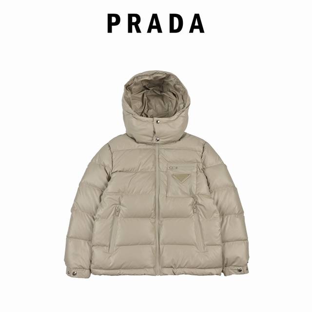 Prada 普拉达 21Fw经典三角标帽子可拆卸羽绒服 此款廓形丰满的羽绒外套采用linea Rossa独特的双层轻质粘合尼龙面料打造，搭配连帽衣领、直裁衣袖和