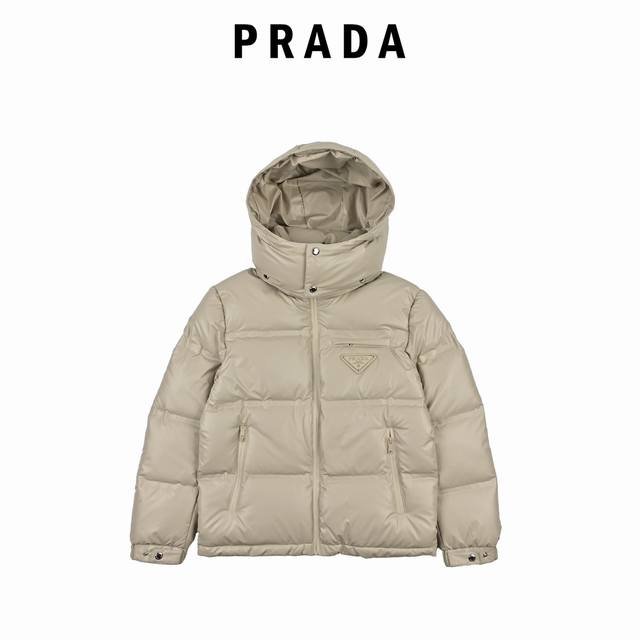 Prada 普拉达 21Fw经典三角标帽子可拆卸羽绒服 此款廓形丰满的羽绒外套采用linea Rossa独特的双层轻质粘合尼龙面料打造，搭配连帽衣领、直裁衣袖和