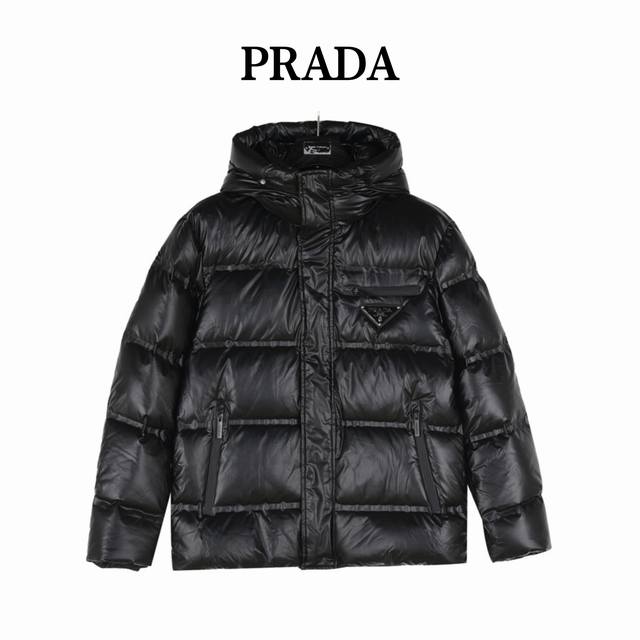 Prada 普拉达 24Fw新款三角标连帽羽绒服 此款廓形丰满的羽绒外套采用linea Rossa独特的双层轻质粘合尼龙面料打造，搭配连帽衣领、直裁衣袖和正面拉