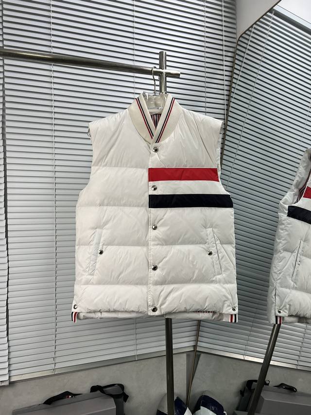 Thom Browne 红白蓝三杠羽绒马甲 这款羽绒马甲采用 90%的优质白鸭绒填充，含绒量高，蓬松度佳，能够有效阻挡寒冷空气的侵袭，为你在冬日提供卓越的保暖效