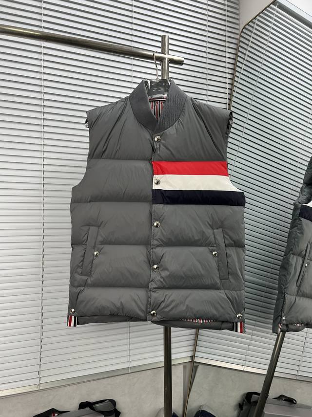 Thom Browne 红白蓝三杠羽绒马甲 这款羽绒马甲采用 90%的优质白鸭绒填充，含绒量高，蓬松度佳，能够有效阻挡寒冷空气的侵袭，为你在冬日提供卓越的保暖效