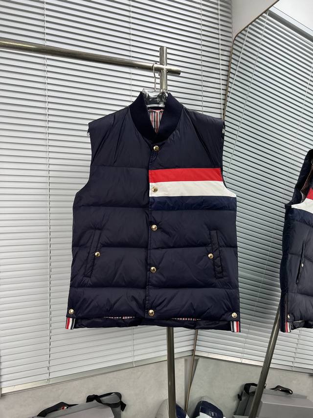 Thom Browne 红白蓝三杠羽绒马甲 这款羽绒马甲采用 90%的优质白鸭绒填充，含绒量高，蓬松度佳，能够有效阻挡寒冷空气的侵袭，为你在冬日提供卓越的保暖效